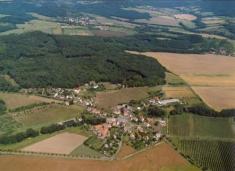 Letecký snímek Chudoslavic z&nbsp;jihozápadní strany. V&nbsp;pozadí Třebušín pod&nbsp;horou Kalich, s&nbsp;odstupem pak Horní Týnec a&nbsp;Dolní Týnec.